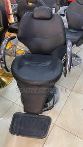 Barber chair with chrome armrests and hydraulic lift, designed for comfort and style in salons.