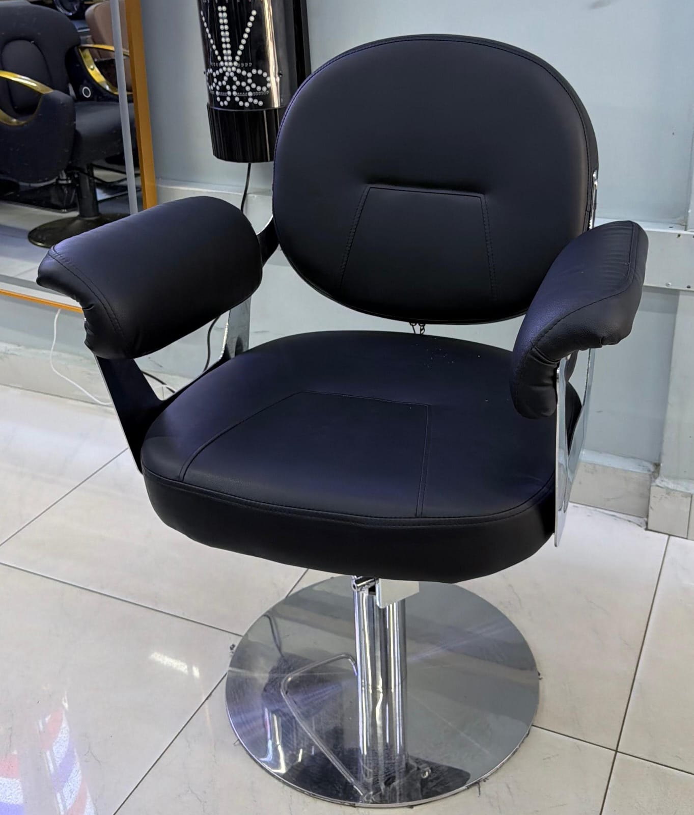 Black salon chair with cushioned seat and metal base.